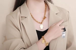 Close-up of golden Hamsa hand pendant and OT toggle clasp on thick chain jewelry set
