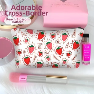 Detailed view of strawberry print makeup bag with zipper and pink beauty accessories