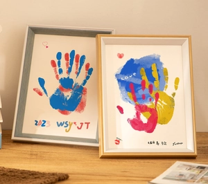 Λεπτομέρεια σετ κορνίζας DIY με πολύχρωμα αποτυπώματα χεριών σε ξύλινο τραπέζι σπιτιού