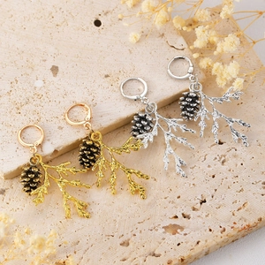 Vintage pine cone and branch earrings in gold and silver finish on stone background