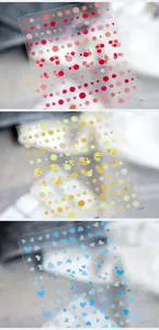 Detailed view of three transparent nail art stickers featuring colorful dots and blue hearts