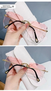 Detail view of pink gradient rimless lenses and gold metal temples on fashion sunglasses