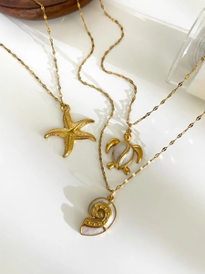 Close-up of 18K gold ocean pendants with starfish, turtle and nautilus shell details