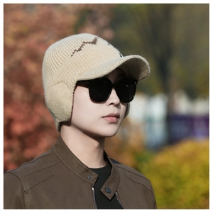 Detail of beige knit winter hat with ear flaps and brown wavy patterns in outdoor setting