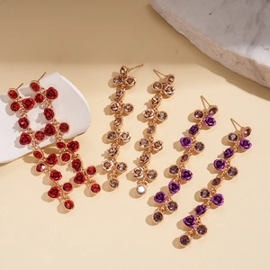 Détail de boucles d'oreilles pendantes avec roses en cristal rouge, champagne et violet
