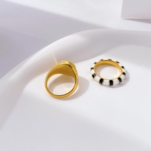 Detail of gold rings with black and white enamel zebra stripes on a minimalist display
