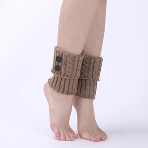 Detail of brown cable knit leg warmers with two decorative black buttons on pure background
