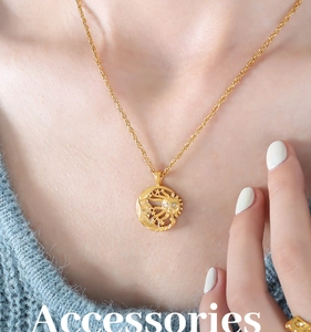 Close-up of a gold sun and moon pendant necklace worn over a blue knitted sweater