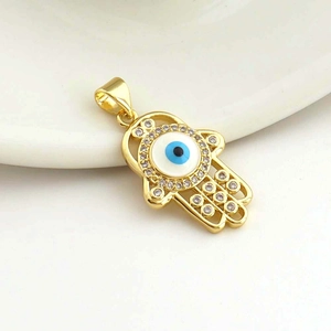Macro shot of gold Hamsa pendant with blue Evil Eye and micro-set cubic zirconia stones