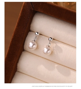 Detail shot of vintage pearl earrings in a luxury jewelry box with mirror silver finish