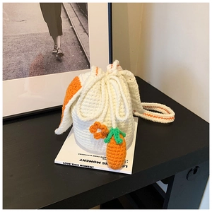 Close-up of handmade bucket bag featuring crochet carrots and orange flowers