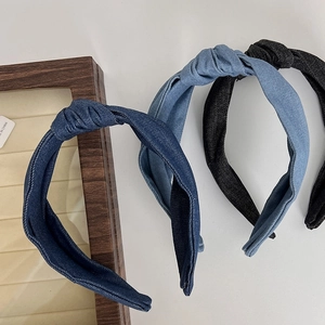 Three knotted denim headbands in blue and black colors on a minimalist white surface
