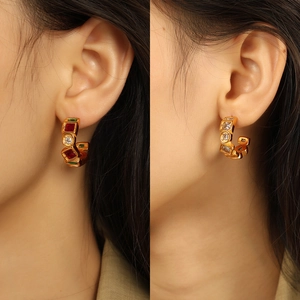 Chic gold-plated C-shaped earrings set with red and green zircons on a female model
