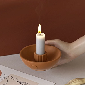 Detail of a terracotta clay candle holder with heart relief and vertical striped base