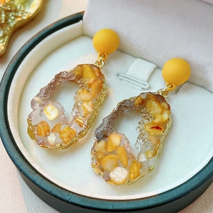 Irregular resin earrings with yellow crystal chips and gold plating on white padding
