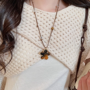 Macro detail of amber-toned resin flower pendant with brown woven adjustable rope chain