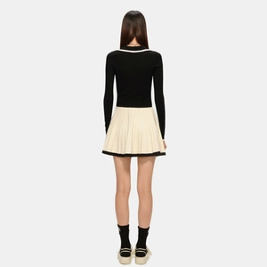 Ensemble vintage style écolière avec haut noir manches longues et jupe plissée blanche