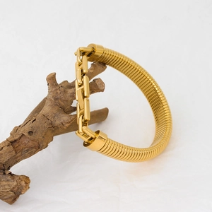 Golden snake chain and rectangular link bracelet layered on natural wood background