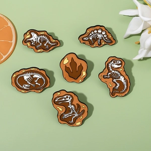 Set of six creative dinosaur fossil skeleton enamel pins on a fresh green background