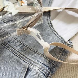 Detail of transparent bag with beige strap and white plastic swivel hook close-up