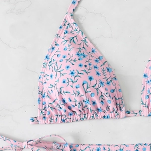 Detailed close-up of pink bikini top with blue floral print and fine stitching details