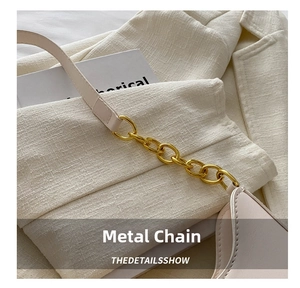 Close-up of golden oval buckle hardware and fine stitching on a beige shoulder bag