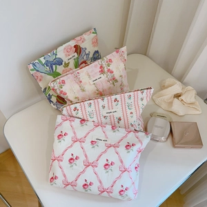 Détail de trousses à maquillage en coton fleuri assorties avec étiquette en tissu