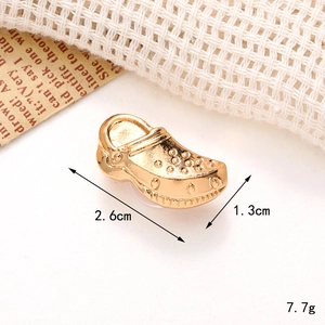 Macro detail of gold metal clog charm showing size 2.6cm and weight 7.7g specifications