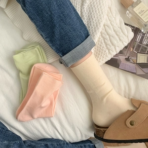Three pairs of cotton crew socks in pastel colors shown with stylish casual clogs