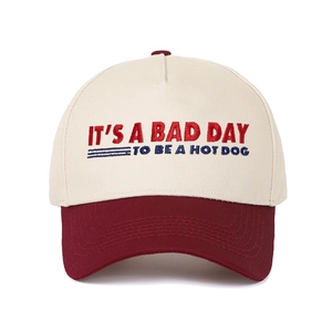 Close-up of retro embroidery text on two-tone cream and red cotton baseball cap