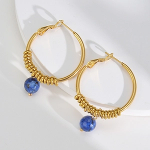 Detail of 14k gold U-shaped earrings with blue stone bead and wire wrap design