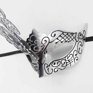 Close-up of silver metal butterfly masquerade mask with black glitter patterns and ribbons