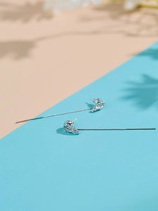 Detail of silver angel wing long tassel earrings with white zircon on minimalist background