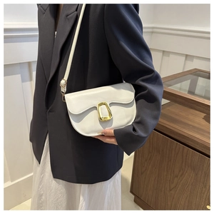 Detail of white faux leather saddle bag featuring a distinctive gold metal clasp closure