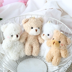 Macro view of four plush teddy bear charms in a white basket with pink dried flowers