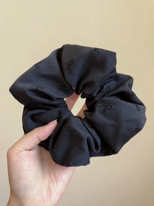 Dettaglio ravvicinato di elastico in tessuto nero carbone con elegante ricamo a fiocco