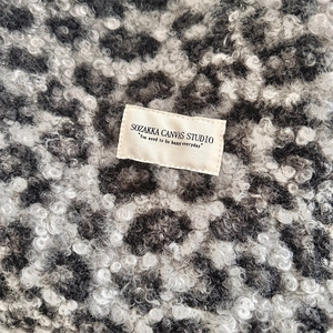 Detail of faux shearling leopard print fabric with brand label and fluffy texture