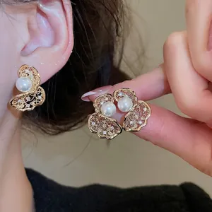 Elegant gold butterfly pearl stud earrings with zircon accents shown on a model