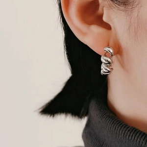 Macro shot of S925 sterling silver hoop earrings with twisted metal texture on ear