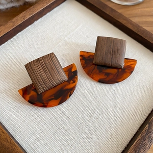Close-up of vintage resin and wood square stud earrings on a white linen display board
