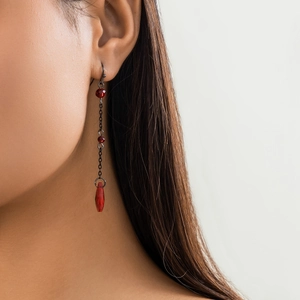 Detail view of gothic red blood droplet tassel earrings on model with dark chains