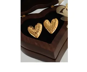 Close-up of golden heart earrings with hammered texture in a wooden gift box