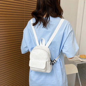 Rear view of a model wearing a white corduroy mini backpack with adjustable buckles