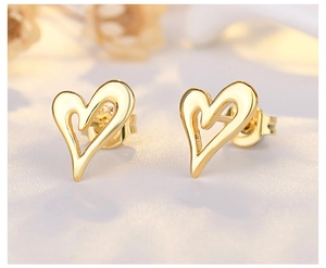 Macro shot of 18K gold plated hollow heart-shaped stud earrings on textured fabric