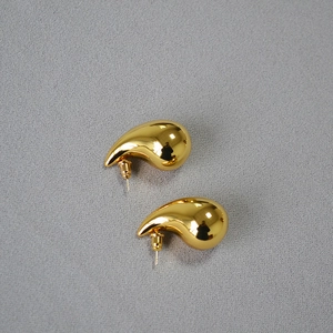Macro shot of high-polished gold water drop earrings with a smooth metallic finish