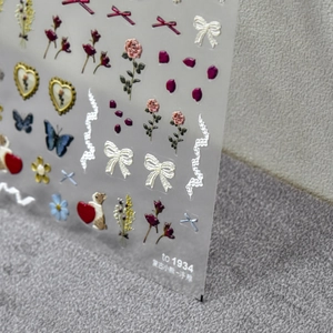 Macro shot of 5D embossed nail stickers featuring vintage roses and butterfly patterns