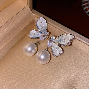 Detailed close-up of butterfly earrings with sparkling crystals and white pearls