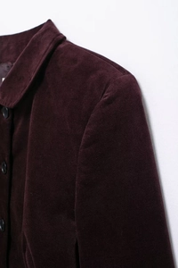 Détail du col et de l'épaule d'une veste en velours bordeaux avec des boutons noirs
