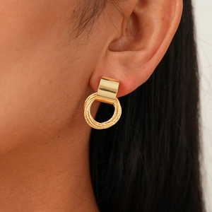 Detail of gold geometric drop earrings with hammered texture on a female model