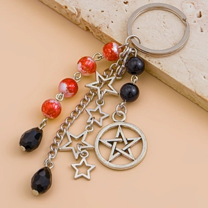 Detail of keychain with silver star pendants and red swirl beads on a stone surface